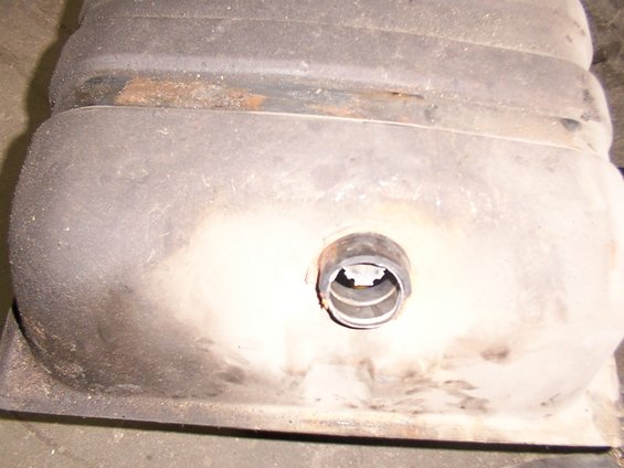 Fuel tank with a circular fitting and some rust on its upper edge