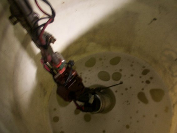 Fuel pump assembly submerged in a tank with yellow liquid