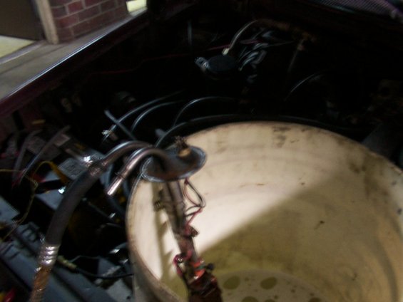 Fuel pump assembly with hoses and wires sitting in a white bucket