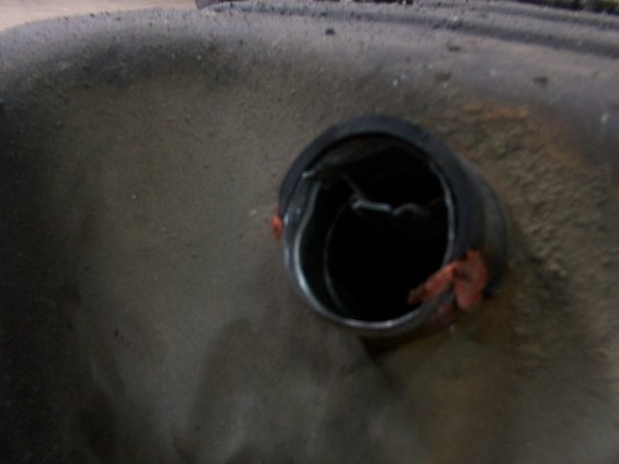 Close-up of a dark, circular opening on a textured surface, possibly a fuel tank