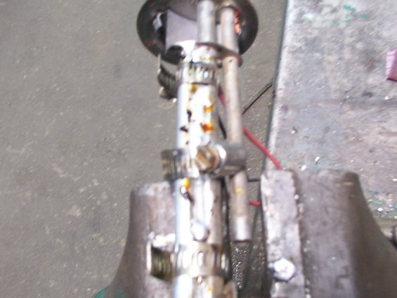 Fuel pump assembly held in a metal vise, showing hoses and electrical wires