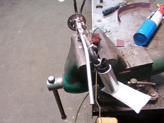 Fuel pump assembly held in a vise with tools on workbench