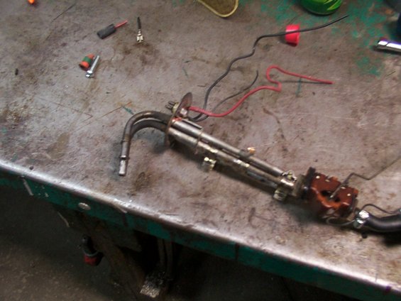 Fuel pump assembly with metal tubes and electrical wires on a workbench