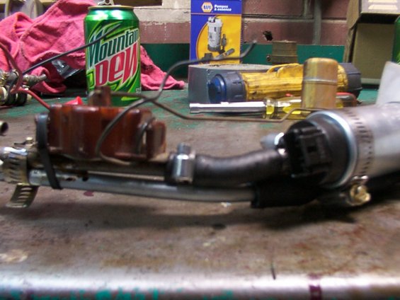 Fuel pump assembly with brown plastic component and metal canister on workbench