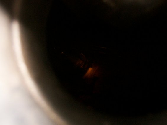 Dark interior of a vehicle, with a blurred orange light reflection on a curved surface