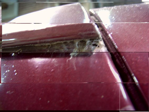 Maroon vehicle's damaged drip rail with debris and rust visible