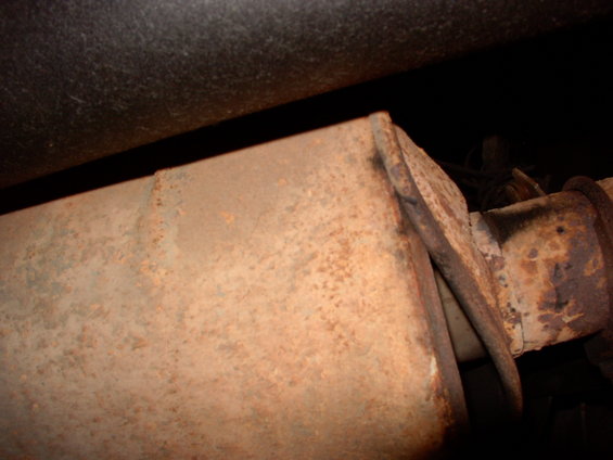 Rusty muffler and exhaust pipe section, close-up view