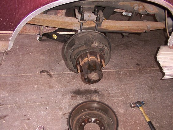 Rear axle brake drum and hub assembly, with leaf springs above. A brake rotor sits on the floor