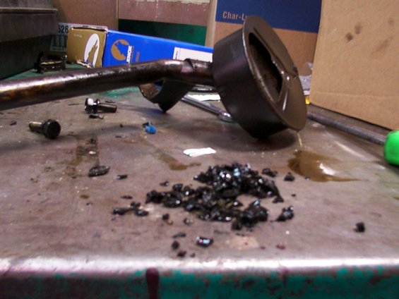 Oil pan with dark debris and oil spill on a workbench
