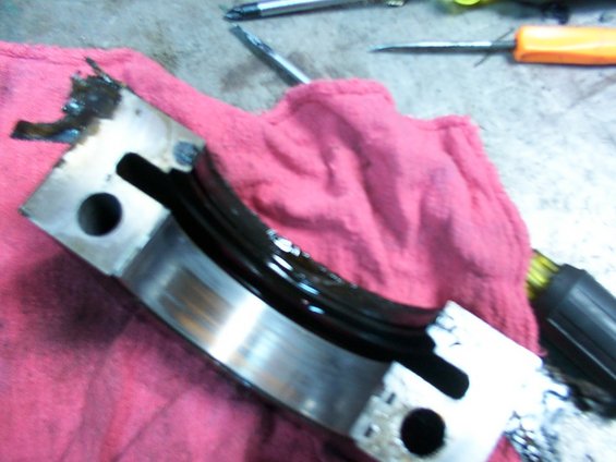 Engine bearing with black oil residue on a pink cloth, tools in background