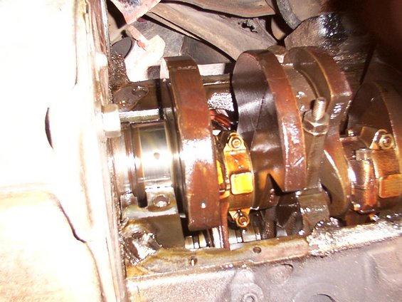 Close-up of engine crankshaft and connecting rod bearings, showing oil and wear