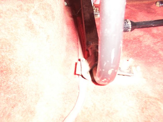 Close-up of a metal bracket attached to a textured surface, with a thick tube in the foreground