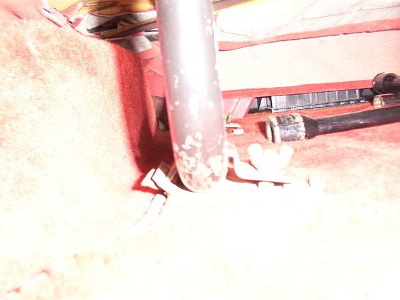 Close-up of seat mounting hardware with red carpet in the background