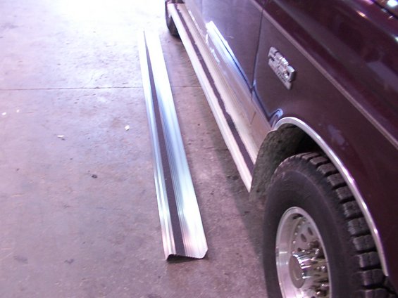 Side view of a maroon truck with a removed running board next to it. The truck has a badge that reads 'F250'