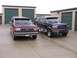 1988 Ford C-350 (Centurion Conversions) - Two Ford Bronco Centurion Conversions are parked in front of storage units, one maroon and one dark blue.