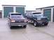 1988 Ford C-350 (Centurion Conversions) - Two Ford SUVs, one purple and one dark blue, are parked outside storage units. The purple SUV has license plate OTV 549.