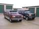 1988 Ford C-350 (Centurion Conversions) - Two Ford Bronco SUVs parked in front of storage units, one maroon and one dark blue.