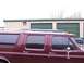 1988 Ford C-350 (Centurion Conversions) - Side view of a maroon van and a blue SUV parked outdoors.