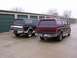 1988 Ford C-350 (Centurion Conversions) - Two Ford SUVs, one maroon and one dark blue, are parked in front of storage units.