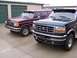 1988 Ford C-350 (Centurion Conversions) - Two Ford trucks, a dark green one in front and a maroon one behind, are parked in front of storage units.