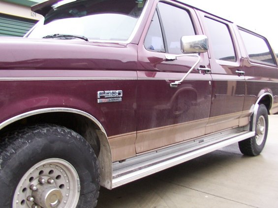 Maroon Ford F-350 extended cab pickup truck with tan lower body trim and running boards