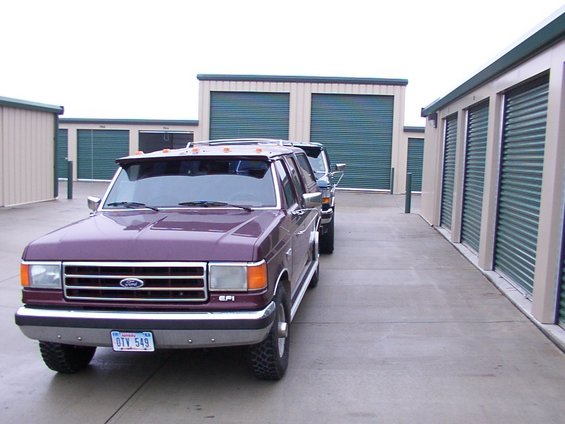 Purple Ford F-Series truck parked in front of storage units, with another truck behind it