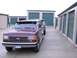 1988 Ford C-350 (Centurion Conversions) - Two Ford F-Series trucks are parked in a row outside storage units.