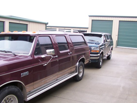 Maroon SUV and dark green SUV parked side-by-side, with storage unit doors in the background