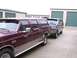 1988 Ford C-350 (Centurion Conversions) - Two SUVs are parked in front of storage units, one maroon and one dark green.