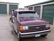 1988 Ford C-350 (Centurion Conversions) - A maroon Ford truck is parked in front of storage units, with another vehicle behind it.