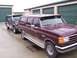 1988 Ford C-350 (Centurion Conversions) - Two Ford trucks, a maroon Centurion Conversion and a dark blue Bronco, are parked in front of storage units.