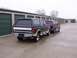 1988 Ford C-350 (Centurion Conversions) - Two extended-cab Ford Bronco Centurion Conversions are parked side-by-side in front of a row of storage units.