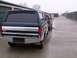 1988 Ford C-350 (Centurion Conversions) - A line of pickup trucks, including a dark green and silver 1988 Ford C-350 Centurion Conversions, are parked outside storage units.