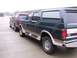 1988 Ford C-350 (Centurion Conversions) - Two Ford Bronco Centurion conversion SUVs are parked side-by-side in front of storage units.