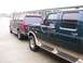 1988 Ford C-350 (Centurion Conversions) - Two Ford trucks, a Bronco and an F-Series, are parked side-by-side in front of storage units.