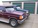 1988 Ford C-350 (Centurion Conversions) - Two Ford trucks, a maroon F-250 and a dark green F-350, are parked in front of storage units.