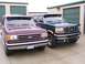 1988 Ford C-350 (Centurion Conversions) - Two Ford trucks, a purple model and a dark green model, are parked side-by-side in front of storage unit doors.