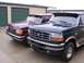 1988 Ford C-350 (Centurion Conversions) - Two Ford trucks, a dark green one in front and a maroon one behind it, are parked outside storage units.