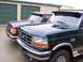 1988 Ford C-350 (Centurion Conversions) - Two Ford trucks are parked side-by-side in front of storage unit doors.