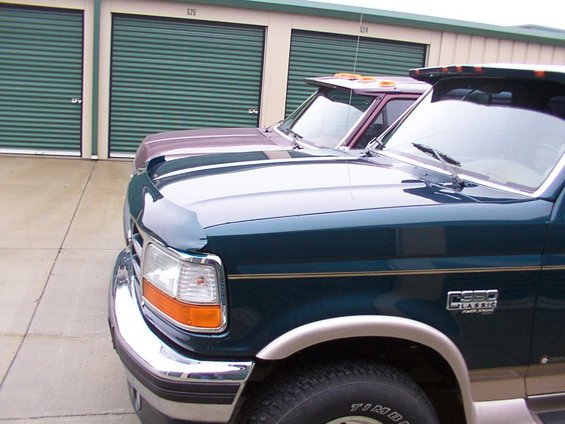 Dark green Ford F-350 Classic truck front quarter panel with chrome bumper and fender trim, parked next to a maroon truck