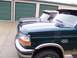 1988 Ford C-350 (Centurion Conversions) - Two Ford trucks are parked in front of storage units, with the front of a dark green F-350 Classic visible.