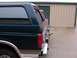 1988 Ford C-350 (Centurion Conversions) - Two SUVs with camper shells are parked side-by-side in front of storage units.