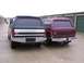 1988 Ford C-350 (Centurion Conversions) - Two Ford Broncos are parked side-by-side in front of storage unit doors.