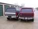 1988 Ford C-350 (Centurion Conversions) - Two Ford trucks, a dark green and a maroon model, are parked side-by-side in front of storage units.