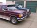 1988 Ford C-350 (Centurion Conversions) - Two Ford trucks, a maroon F-350 and a dark green model, are parked in front of storage units.