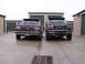 1988 Ford C-350 (Centurion Conversions) - Two Ford trucks are parked in front of storage units on a cloudy day.