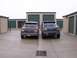 1988 Ford C-350 (Centurion Conversions) - Two Ford trucks are parked in front of storage units. The blue truck's grille suggests a 1992 model year.