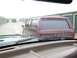 1988 Ford C-350 (Centurion Conversions) - View from inside a vehicle looking out at a maroon SUV with a camper shell parked in a storage unit facility.