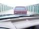 1988 Ford C-350 (Centurion Conversions) - A maroon pickup truck is seen from inside another vehicle, parked in a row of storage units.