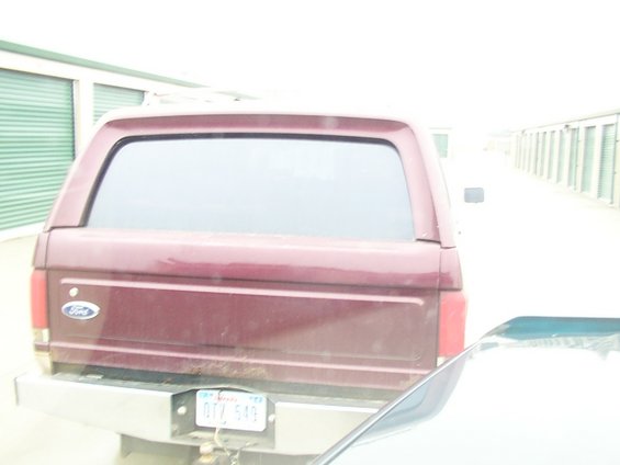 Rear view of a maroon 1988 Ford C-350 (Centurion Conversions) pickup truck with a camper shell. License plate is visible
